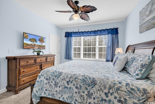 bedroom with ceiling fan, baseboards, a textured ceiling, and light colored carpet