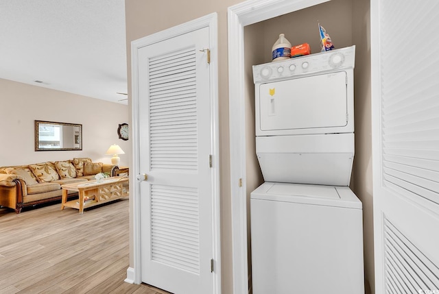 laundry area with visible vents, light wood-type flooring, stacked washing maching and dryer, and laundry area