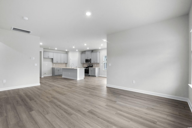 4295 Falls Oaks St, Myrtle Beach, SC 29579 - unfurnished living room with a sink, baseboards, visible vents, and light wood-type flooring