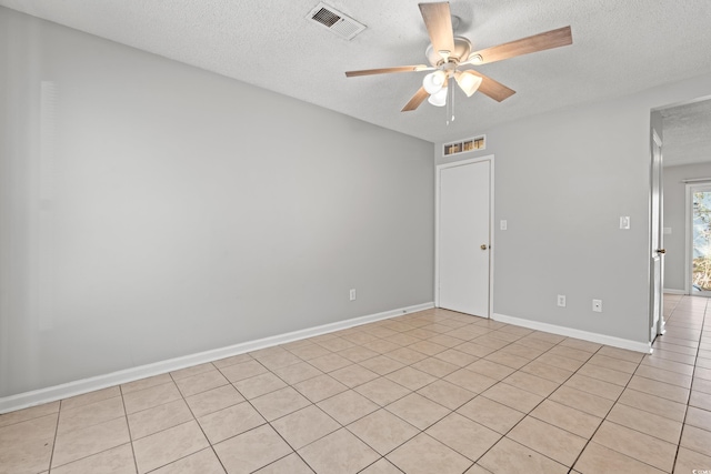 empty room with baseboards, a ceiling fan, visible vents, and a textured ceiling