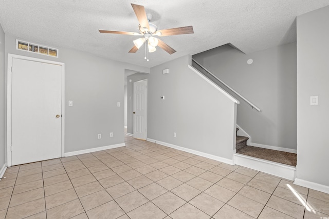 unfurnished living room featuring ceiling fan, stairway, visible vents, and a textured ceiling