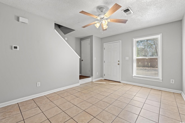 foyer entrance with visible vents, a textured ceiling, baseboards, and a ceiling fan