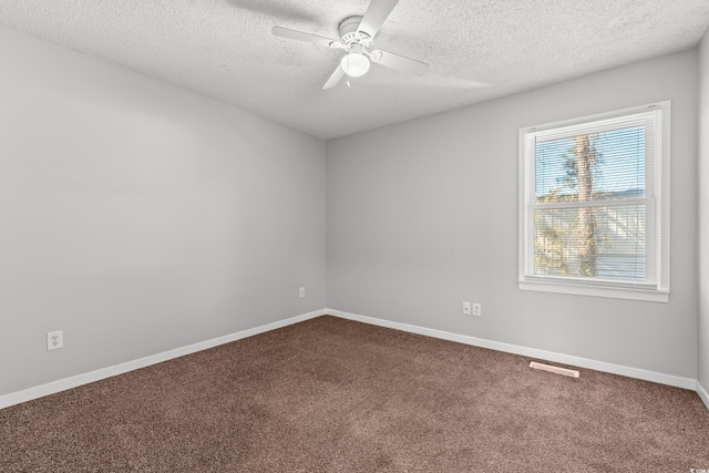 empty room featuring visible vents, a ceiling fan, a textured ceiling, dark carpet, and baseboards