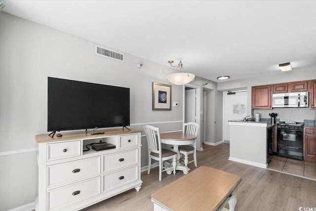 living room with visible vents, light wood-style flooring, and baseboards