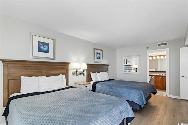 bedroom with light wood-style floors, baseboards, visible vents, and ensuite bathroom