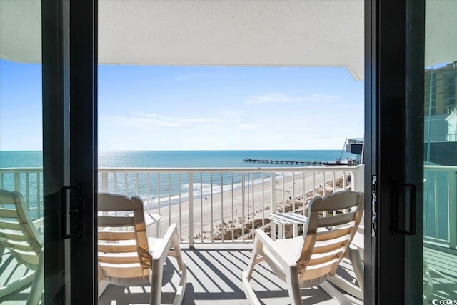 balcony featuring a water view and a beach view