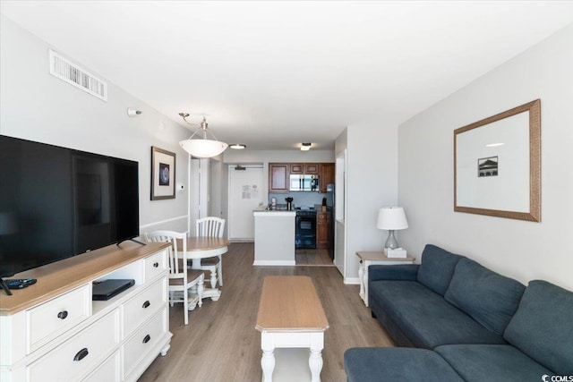 living area with baseboards, visible vents, and light wood-style floors