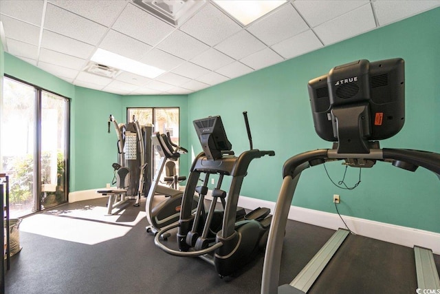 exercise room with a drop ceiling, visible vents, and baseboards