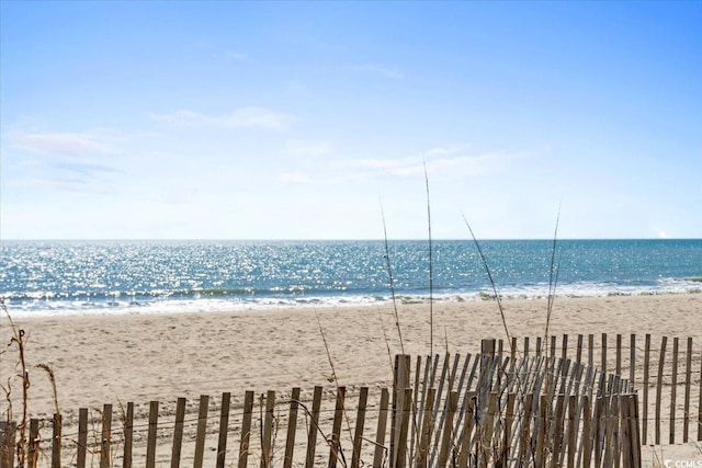 water view featuring fence and a view of the beach