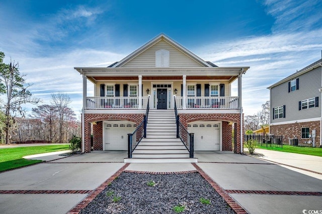 raised beach house with brick siding, stairway, covered porch, and concrete driveway