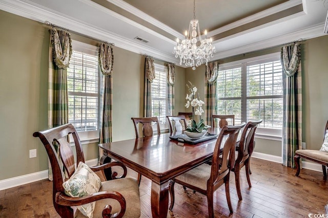 dining space featuring a wealth of natural light, visible vents, a raised ceiling, and hardwood / wood-style floors