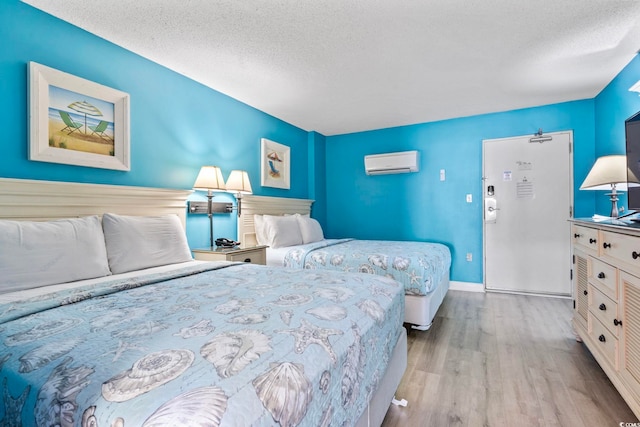 201 S Ocean Blvd Unit 217, Myrtle Beach, SC 29577 - bedroom featuring a wall mounted air conditioner, wood finished floors, a textured ceiling, and baseboards