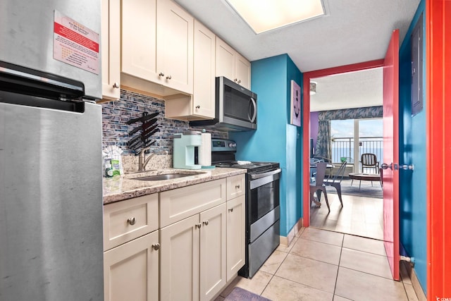 201 S Ocean Blvd Unit 217, Myrtle Beach, SC 29577 - kitchen featuring stainless steel appliances, backsplash, light tile patterned floors, a sink, and white cabinets