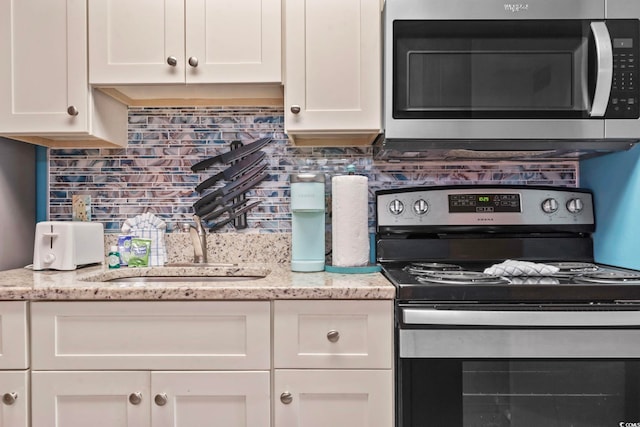 201 S Ocean Blvd Unit 217, Myrtle Beach, SC 29577 - kitchen featuring stainless steel appliances, white cabinets, tasteful backsplash, and light stone counters