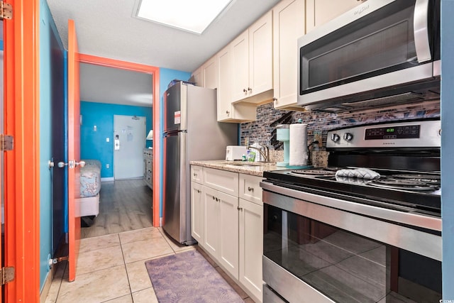 201 S Ocean Blvd Unit 217, Myrtle Beach, SC 29577 - kitchen with stainless steel appliances, a sink, decorative backsplash, white cabinetry, and light stone counters