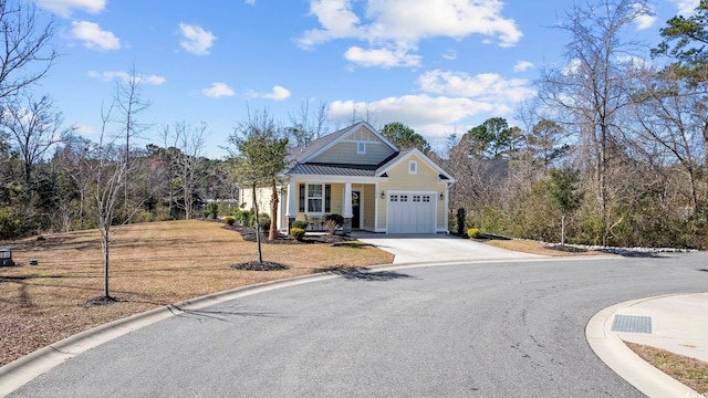 craftsman house featuring a garage, concrete driveway, metal roof, a standing seam roof, and a front yard