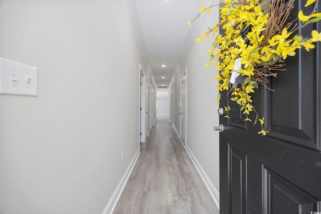 hall with light wood-type flooring, crown molding, baseboards, and recessed lighting