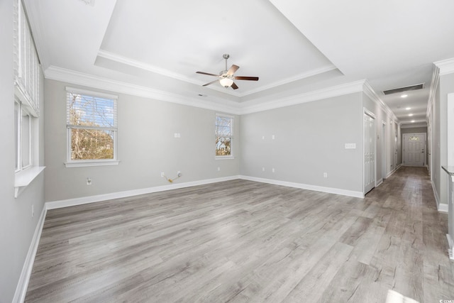 unfurnished room featuring ornamental molding, a tray ceiling, light wood-type flooring, and visible vents