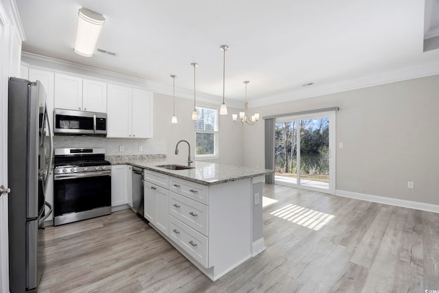 kitchen with stainless steel appliances, a peninsula, a sink, visible vents, and ornamental molding