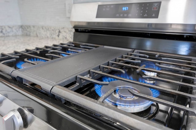 interior details featuring backsplash and stainless steel range with gas cooktop