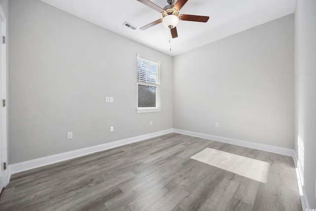 empty room with a ceiling fan, baseboards, visible vents, and wood finished floors