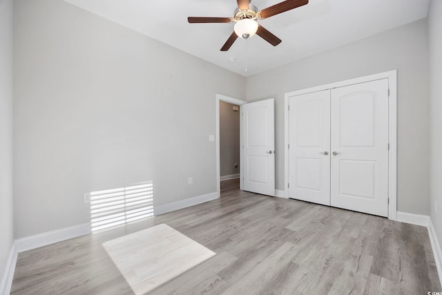 unfurnished bedroom featuring light wood-style flooring, baseboards, ceiling fan, and a closet