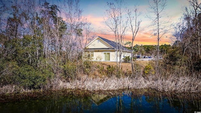 back of property at dusk featuring a water view