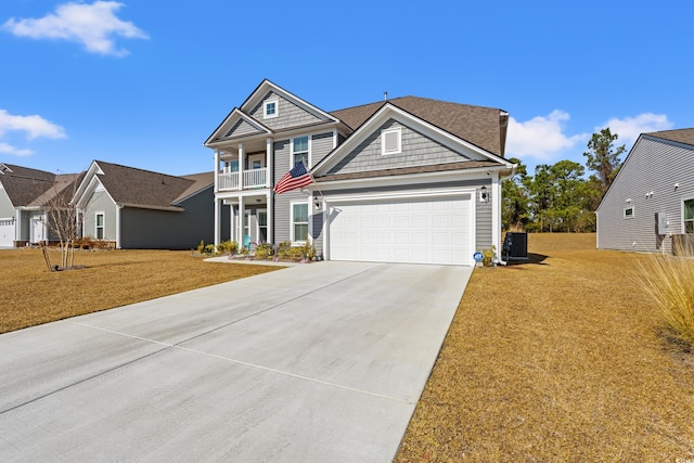 view of front of property featuring a balcony, cooling unit, driveway, a front lawn, and a garage