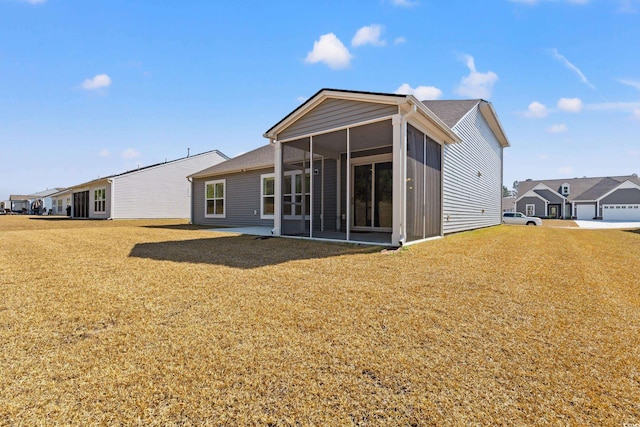 rear view of house with a lawn and a sunroom