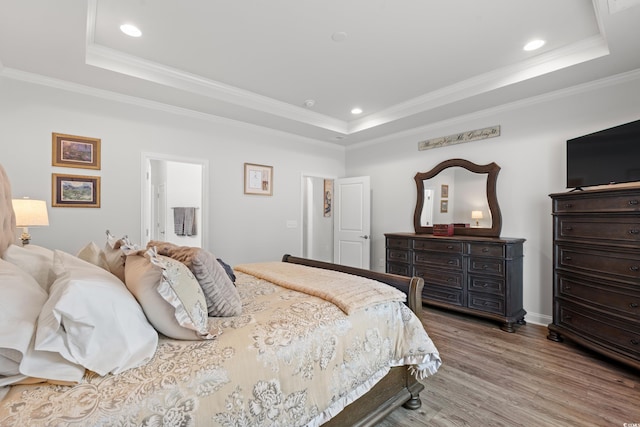 bedroom featuring a tray ceiling, recessed lighting, wood finished floors, and ornamental molding