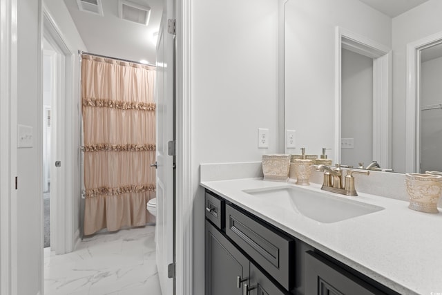 bathroom featuring vanity, toilet, visible vents, and marble finish floor