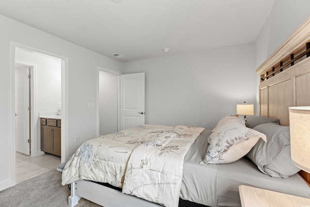 bedroom featuring visible vents, light colored carpet, marble finish floor, and ensuite bathroom