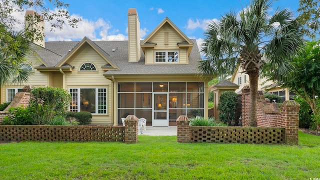 back of house with a yard, a chimney, and a sunroom