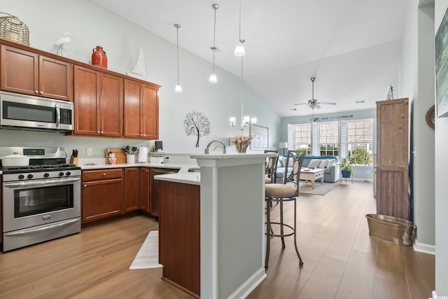 kitchen featuring a breakfast bar, open floor plan, a peninsula, stainless steel appliances, and light wood-type flooring