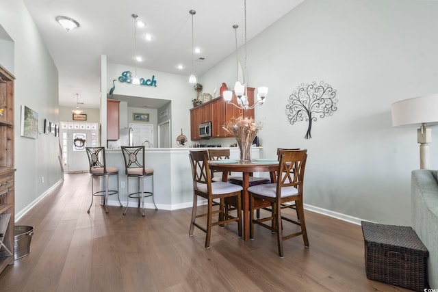 dining area with dark wood-style floors, a high ceiling, baseboards, and a notable chandelier