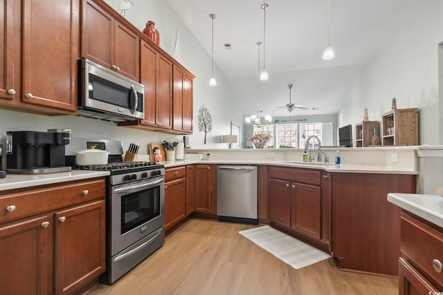 kitchen with light wood finished floors, stainless steel appliances, light countertops, a sink, and a peninsula