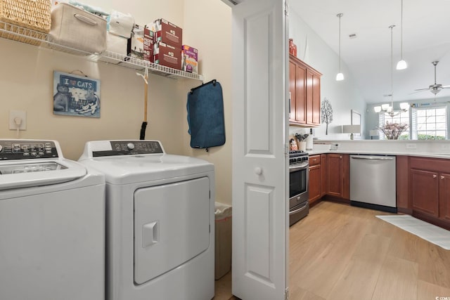 washroom featuring laundry area, washing machine and dryer, light wood finished floors, and ceiling fan with notable chandelier