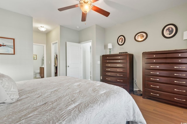 bedroom featuring ceiling fan, ensuite bath, and wood finished floors