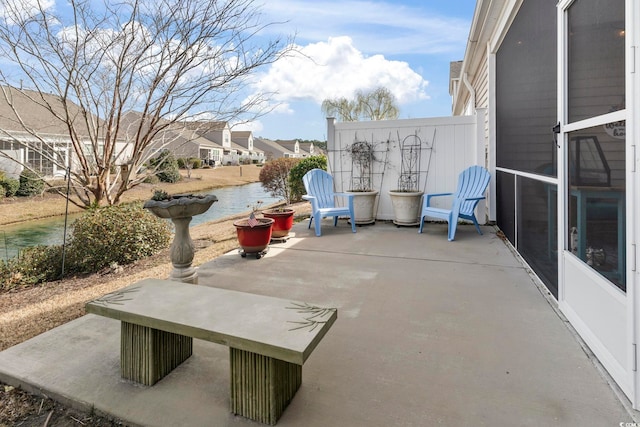 view of patio / terrace featuring a water view and fence