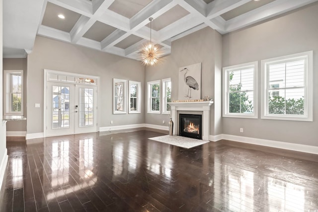 unfurnished living room with baseboards, coffered ceiling, a high ceiling, a fireplace with flush hearth, and french doors