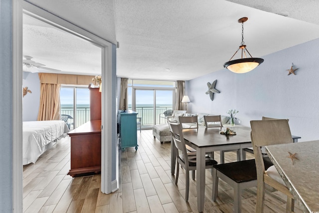 2007 S Ocean Blvd Unit 2006, Myrtle Beach, SC 29577 - dining area with a textured ceiling, a water view, a ceiling fan, wood finished floors, and a wood stove