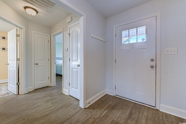 entryway with baseboards, visible vents, and wood finished floors