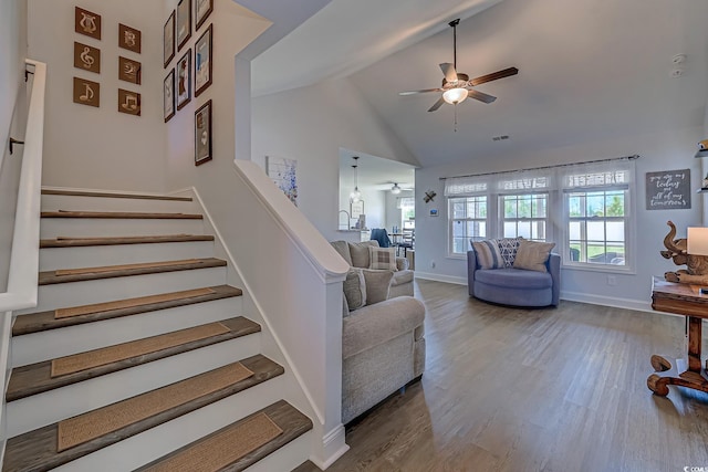 stairs featuring ceiling fan, high vaulted ceiling, wood finished floors, visible vents, and baseboards