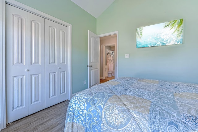 bedroom with a closet, vaulted ceiling, and wood finished floors