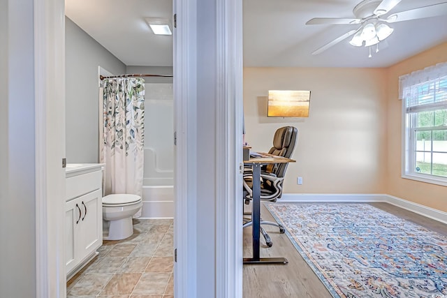 interior space featuring baseboards, ceiling fan, vanity, and toilet