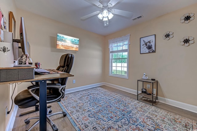 office featuring ceiling fan, wood finished floors, visible vents, and baseboards