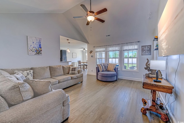 living area with visible vents, ceiling fan, wood finished floors, high vaulted ceiling, and baseboards