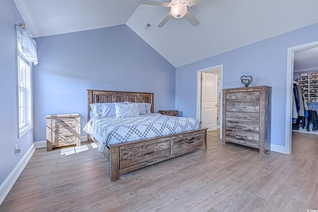 bedroom with vaulted ceiling, wood finished floors, visible vents, and a walk in closet