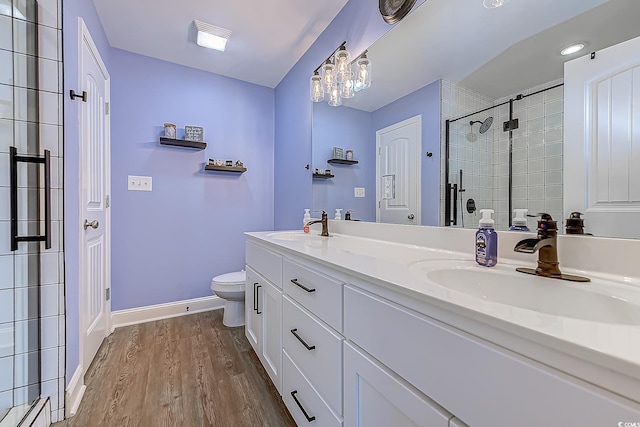 full bathroom featuring toilet, a stall shower, a sink, wood finished floors, and baseboards