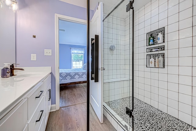 ensuite bathroom featuring wood finished floors, vanity, baseboards, a shower stall, and ensuite bath